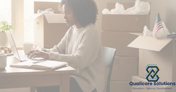 African American Woman typing on a laptop with moving boxes in the background